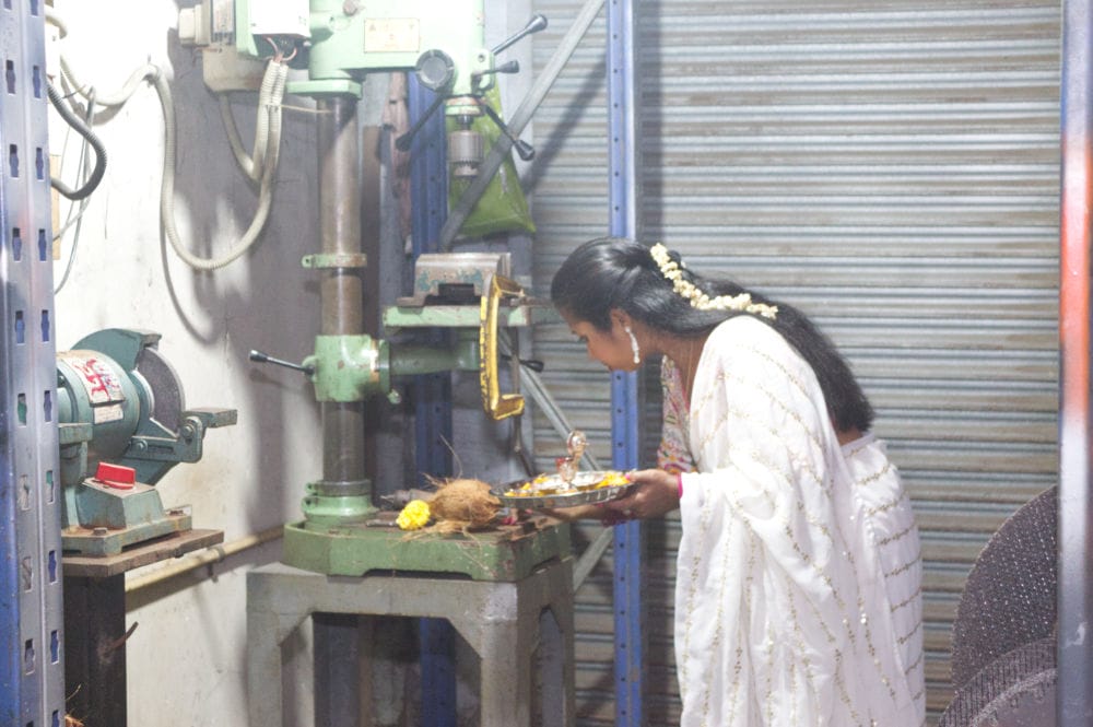 Woman performing ritual near industrial machines.