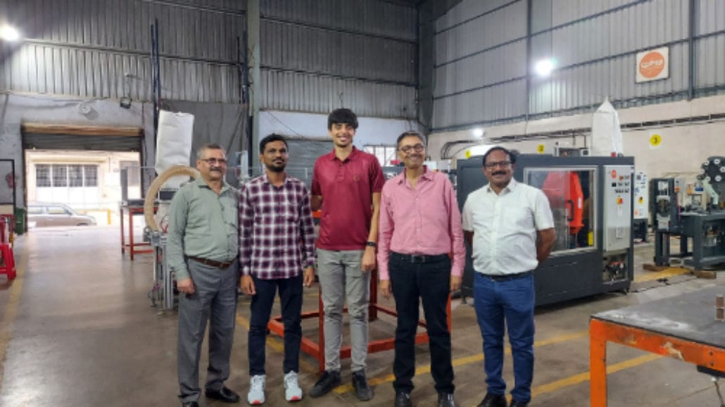 Group of five men in an industrial workshop.