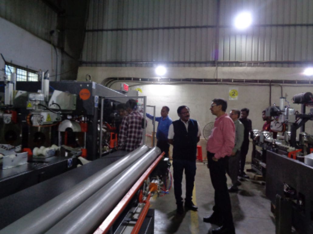People in factory observing machinery operations.