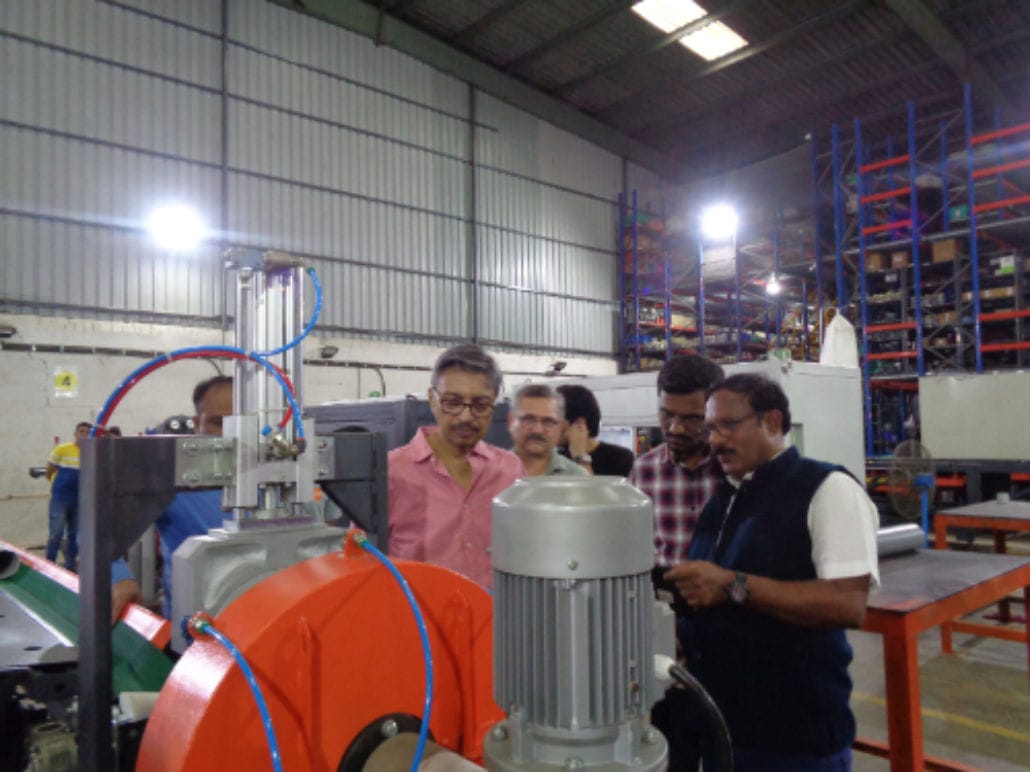 Group inspecting industrial machinery in warehouse