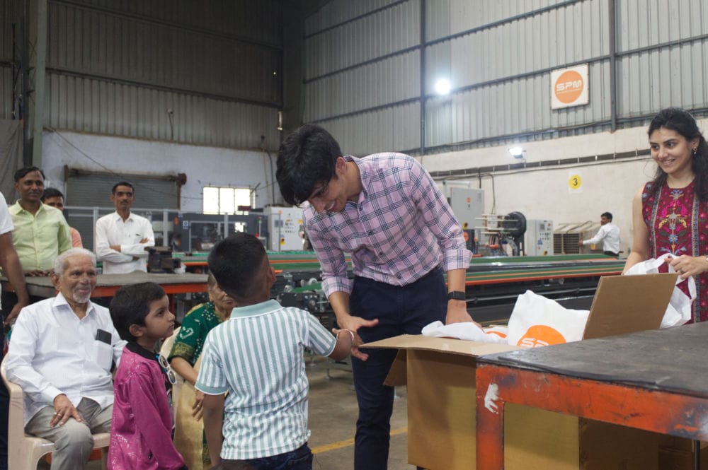 People distributing gifts to children at factory event.