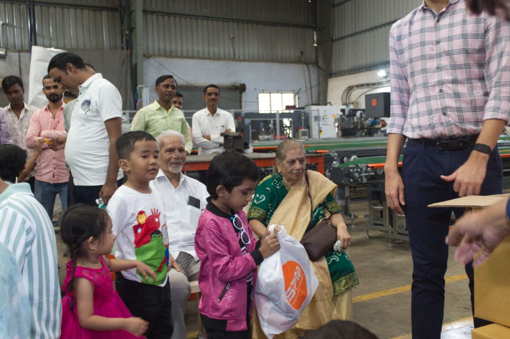 Group at factory, kids receiving gifts.
