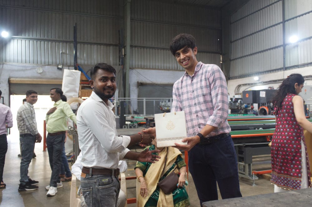 Two men exchanging a gift in an industrial setting.
