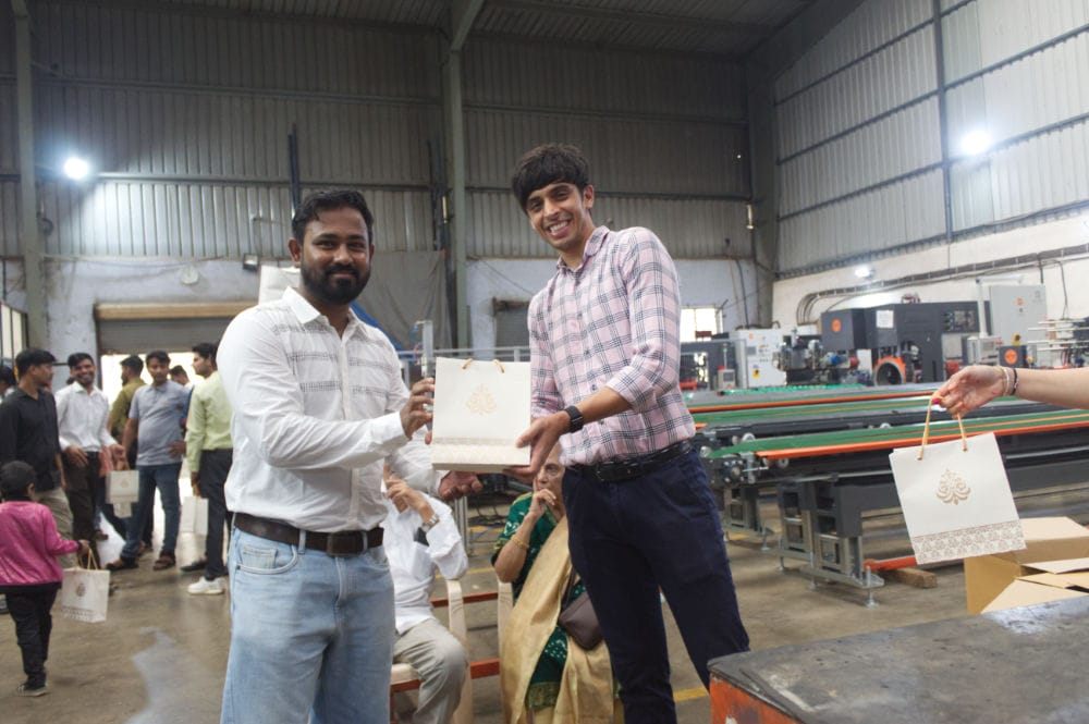 People exchanging gift bags at factory event.