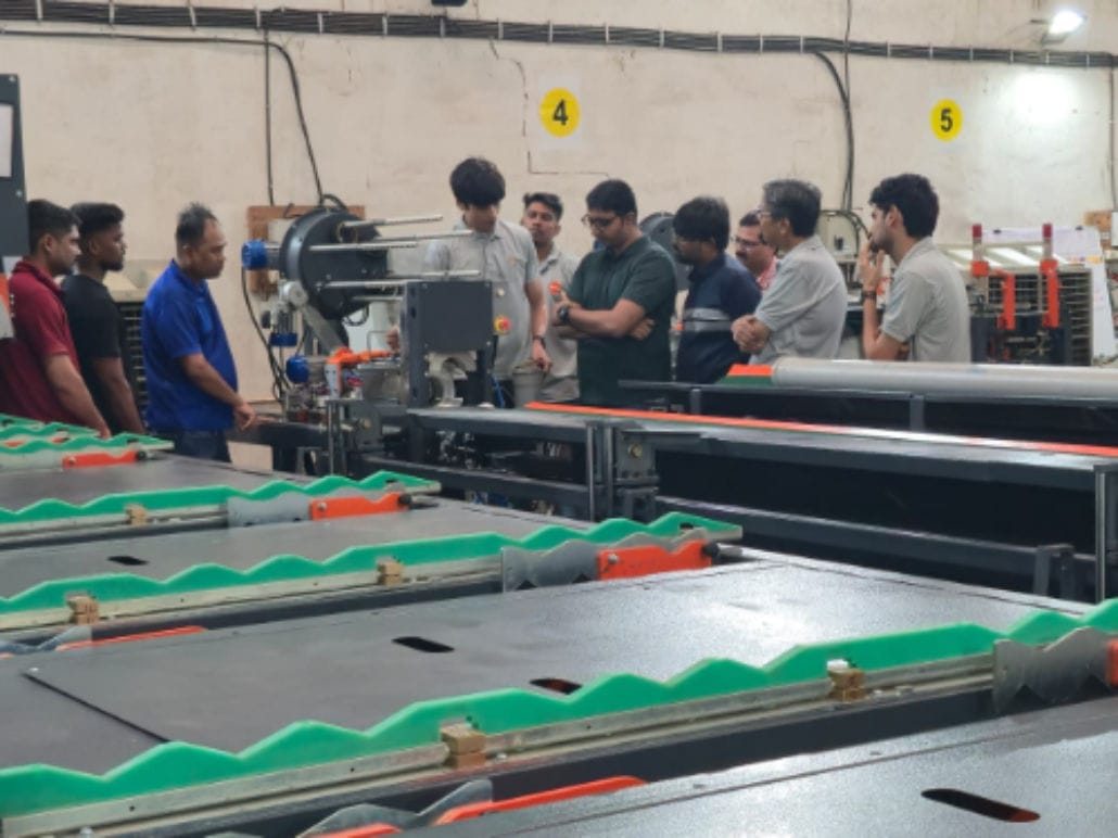 People observing machine operation in factory setting.