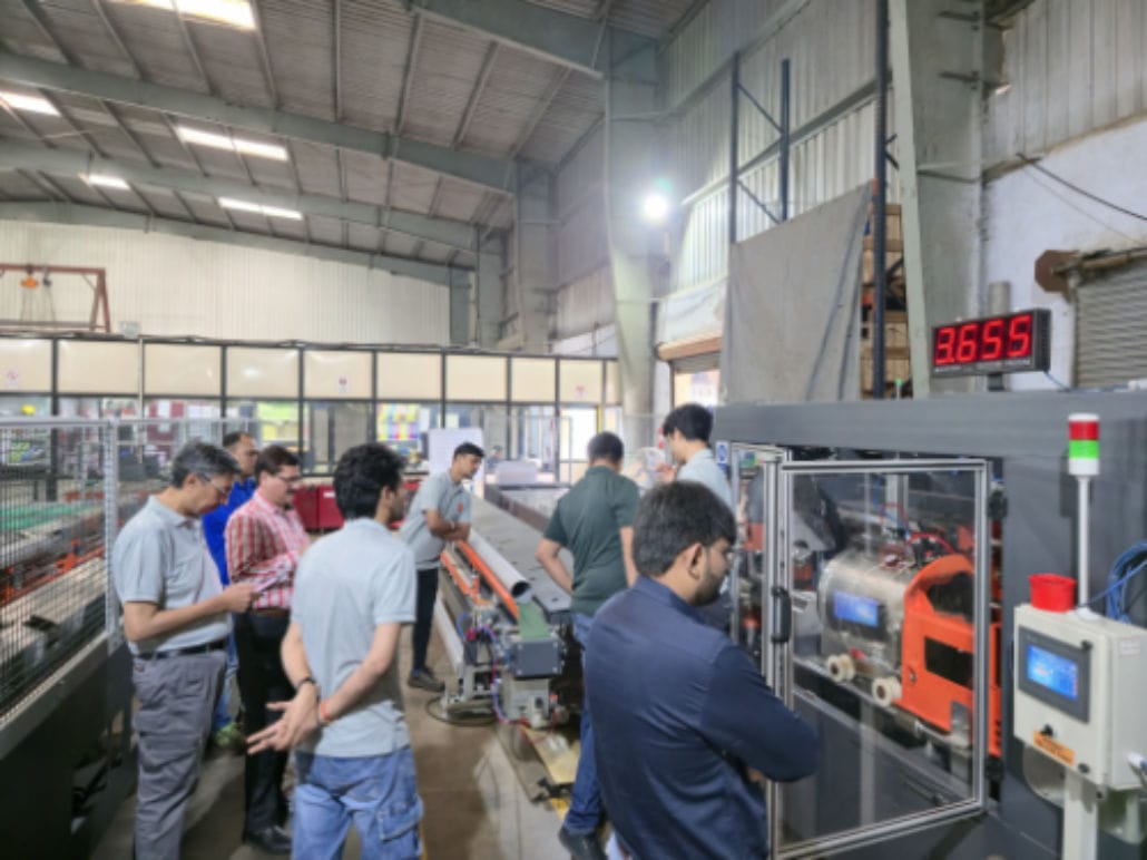 Team observing industrial machine operation.