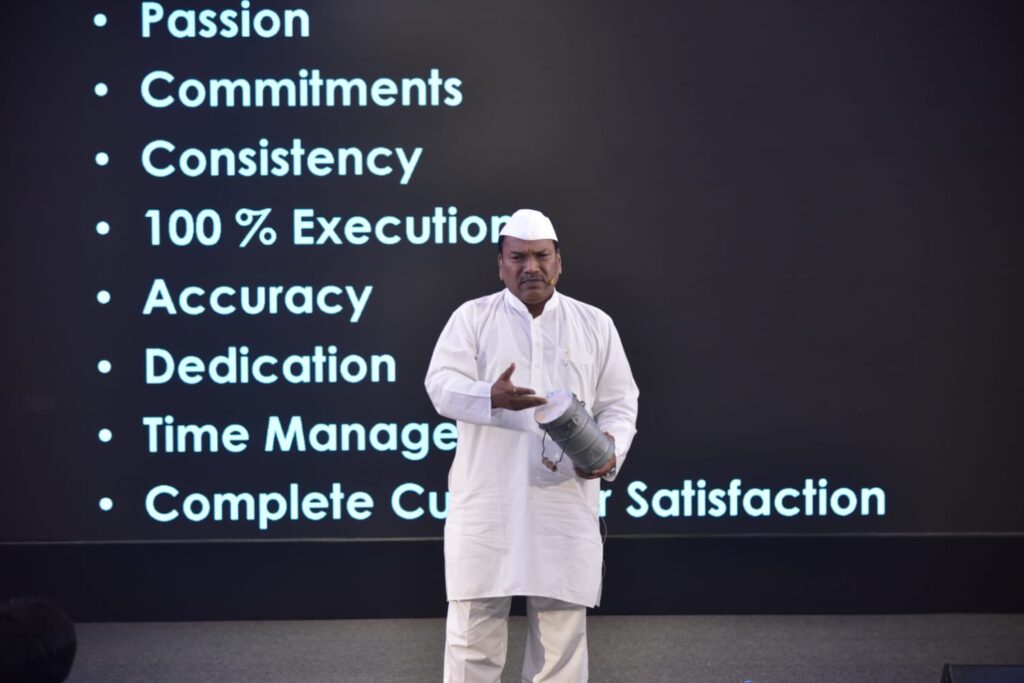 Man in white presents beside values list on screen