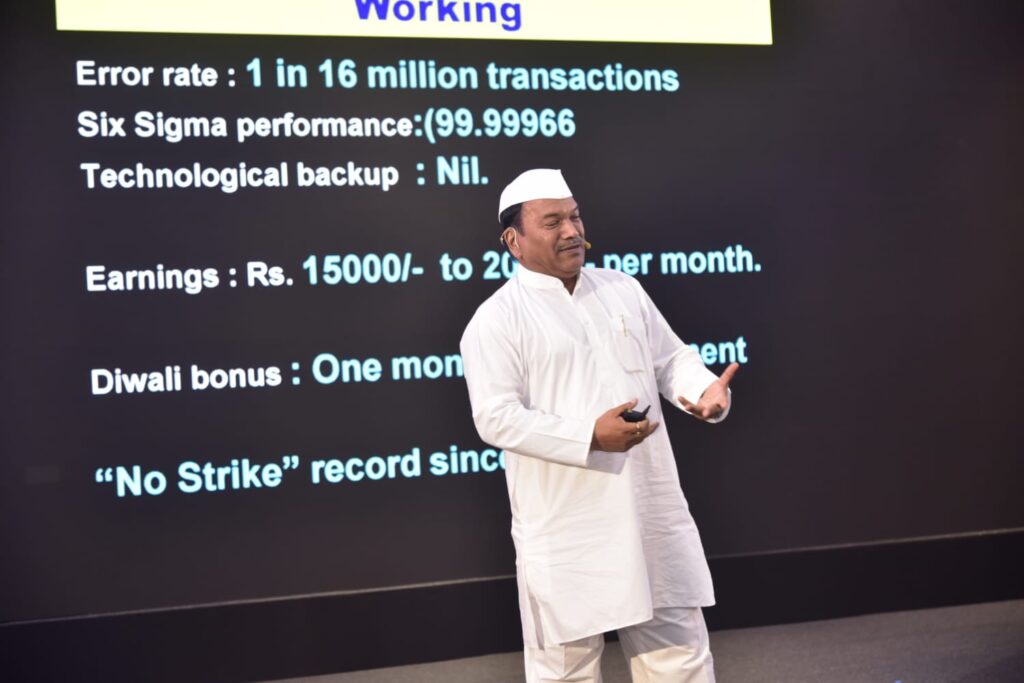 Man presenting beside workplace performance statistics slide