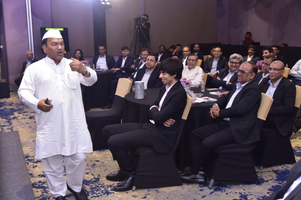 Speaker in white addresses seated business audience at conference