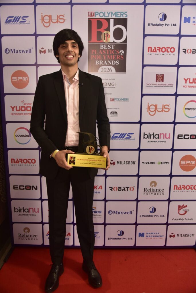 Man holding plastics industry award before sponsor backdrop
