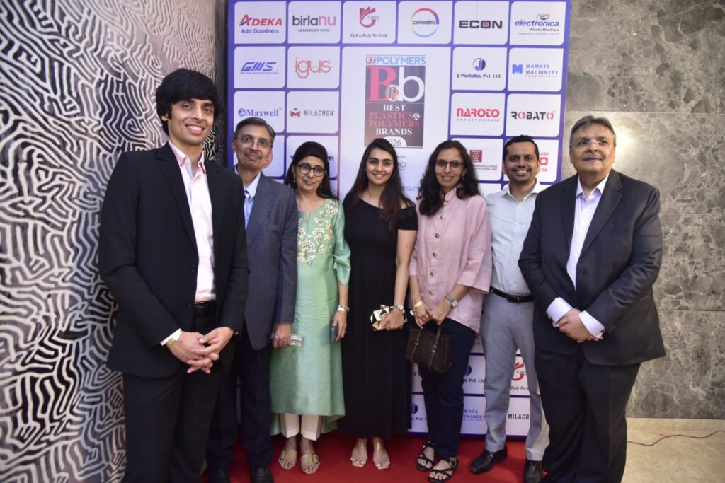 Seven attendees pose at plastics industry awards backdrop.