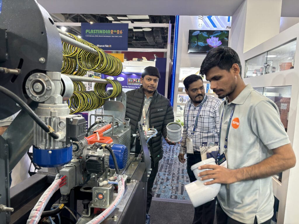 Men examining plastic extrusion machine at trade show