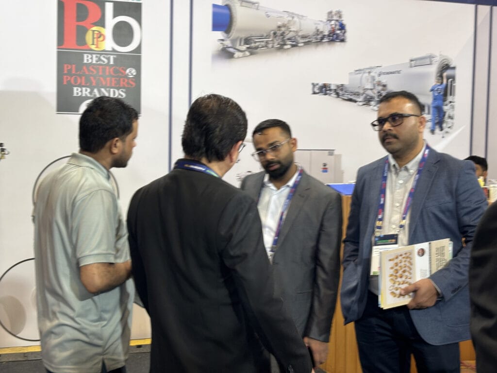 Business professionals discussing at plastics industry trade show booth