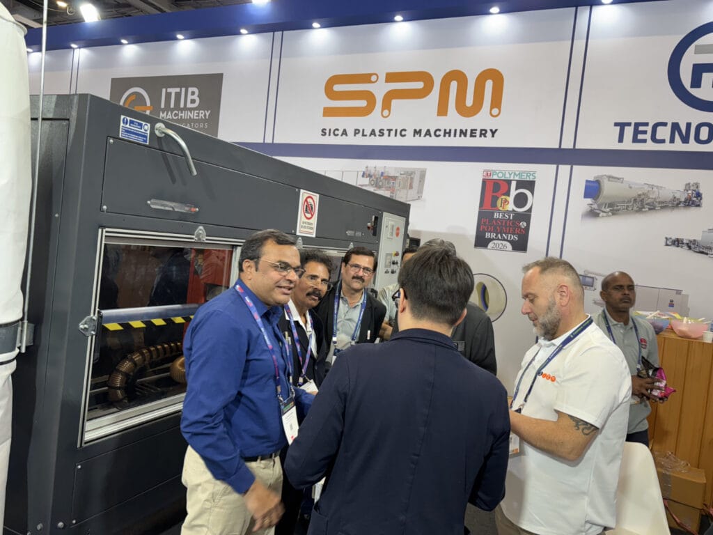 Men discussing plastic machinery at trade show booth