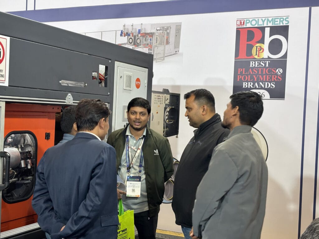 Men discussing industrial plastic machinery at trade show