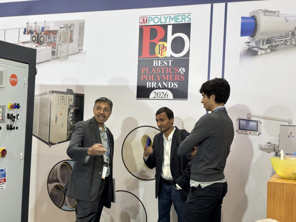 Men discussing polymer machinery at trade show booth