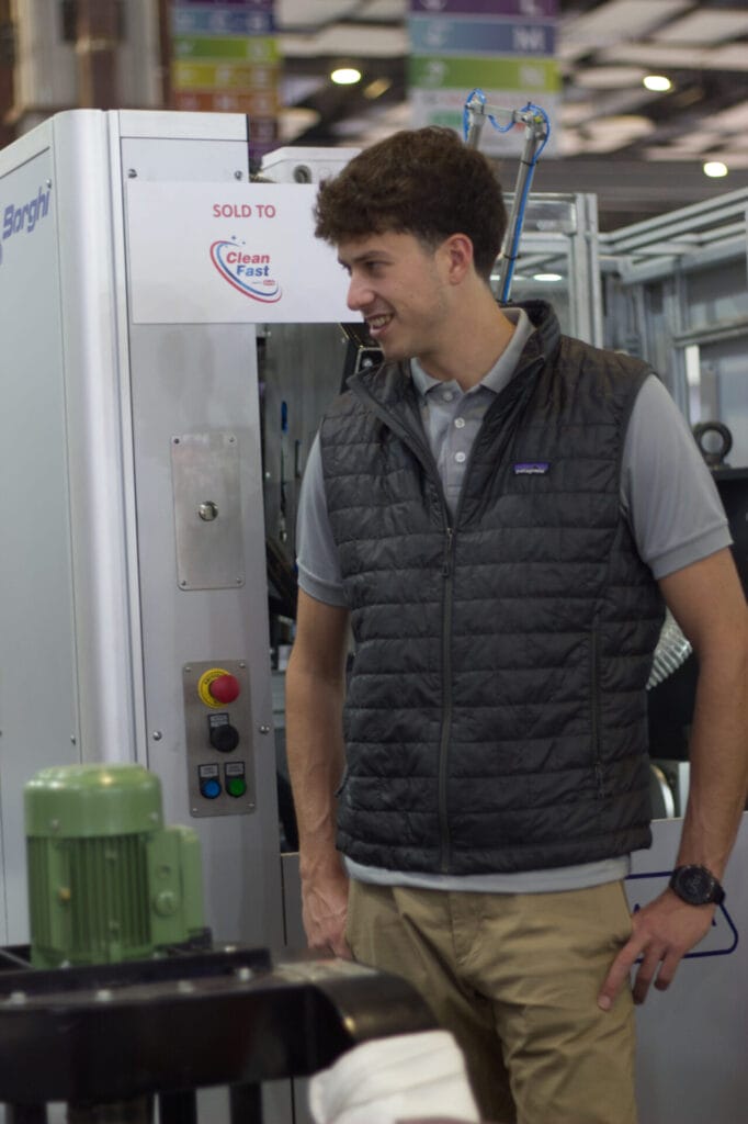 Man smiling beside industrial machine in factory