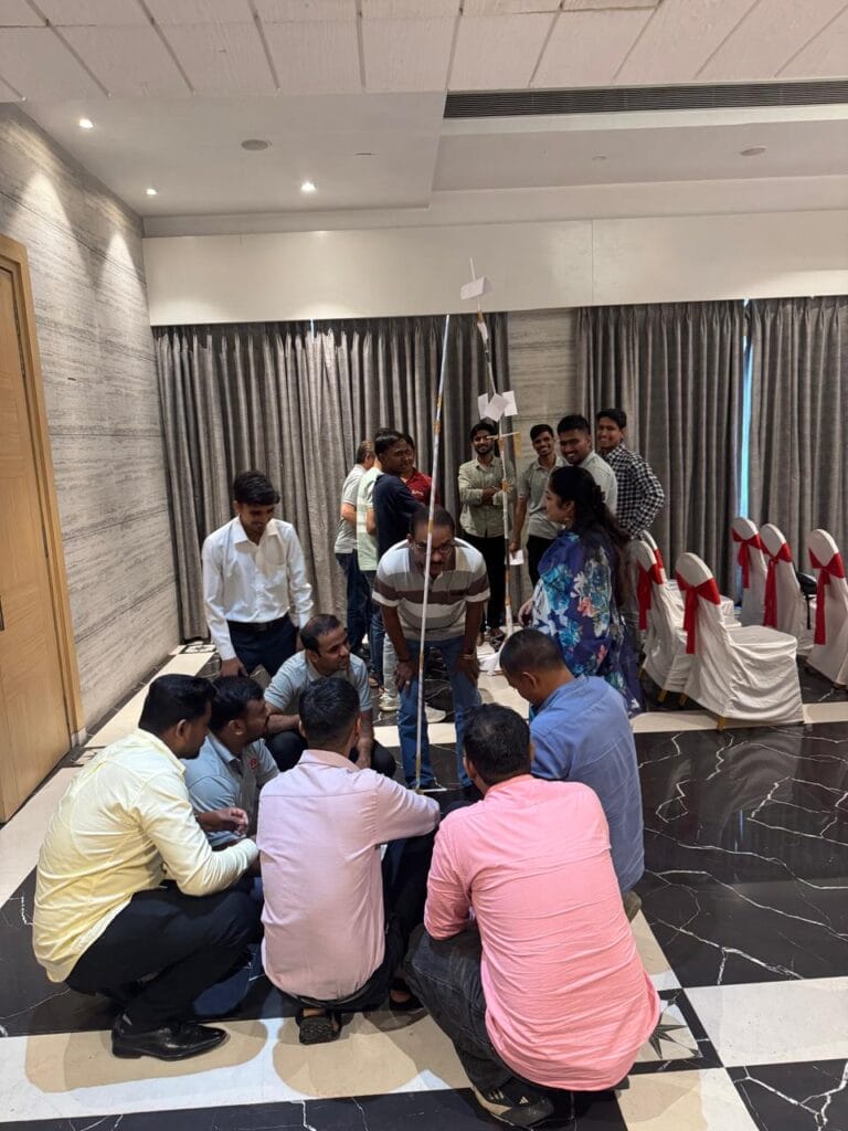 Colleagues collaborate on a tall indoor team-building tower challenge.