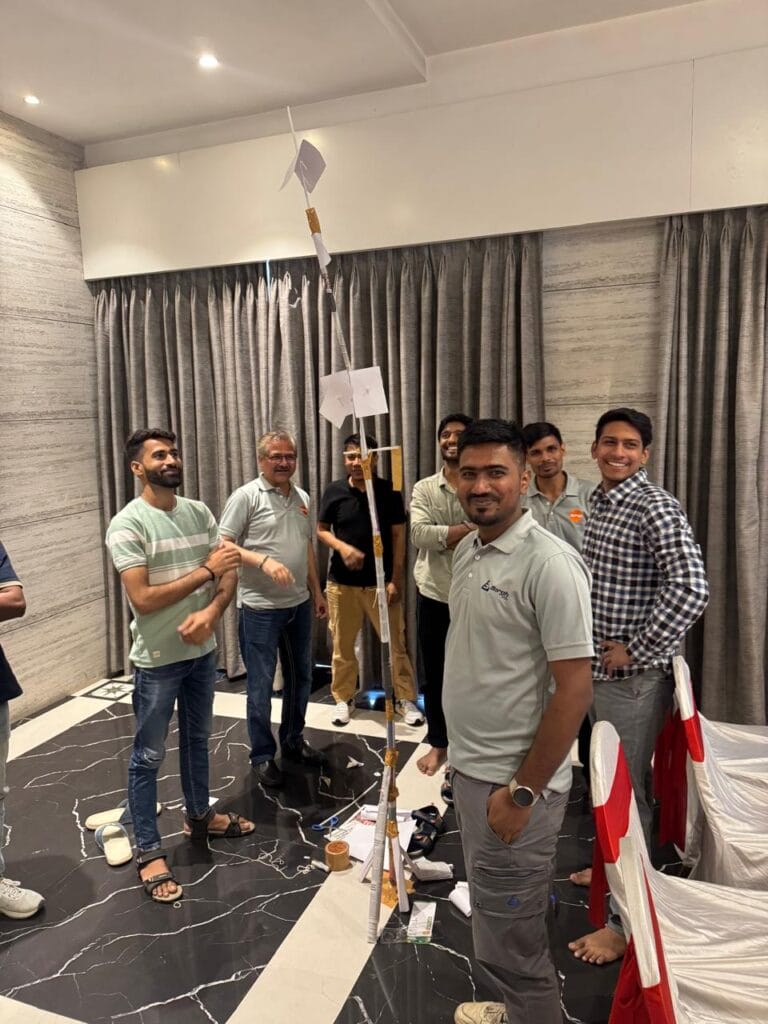 Group of men standing beside a tall paper rocket