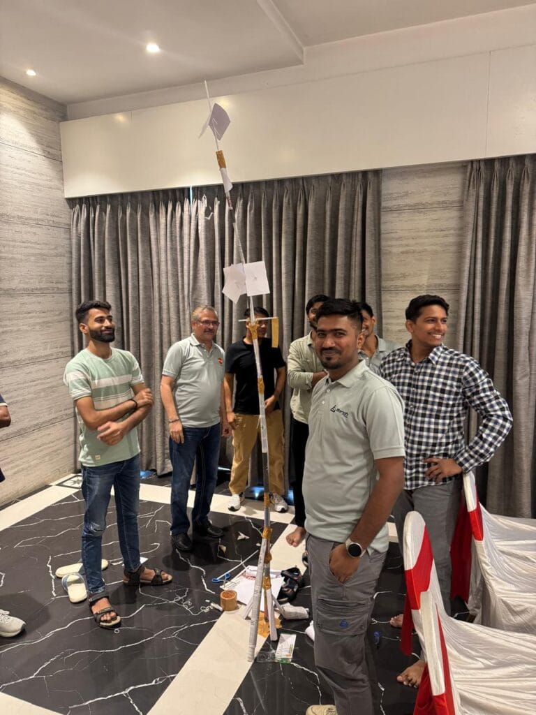 Group of men beside a handmade paper tower