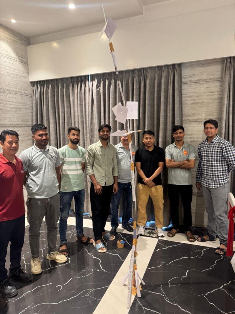 Group displays tall handmade paper tower indoors