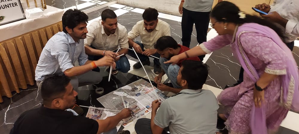 Group collaborates on a newspaper and straw building activity