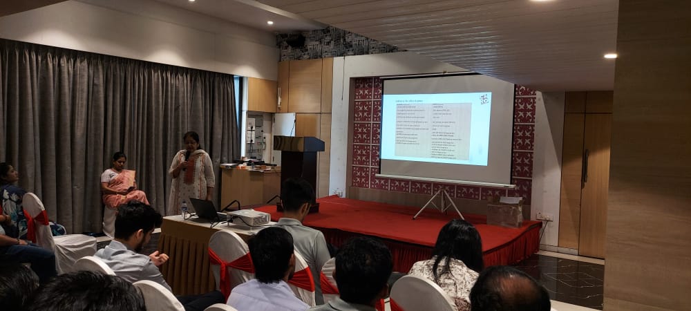 Woman presents slides to seated audience in conference room