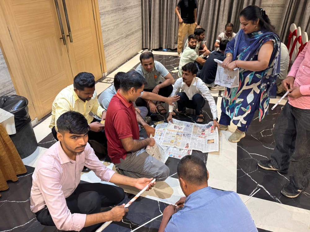 People assemble rolled papers on a tiled floor indoors.